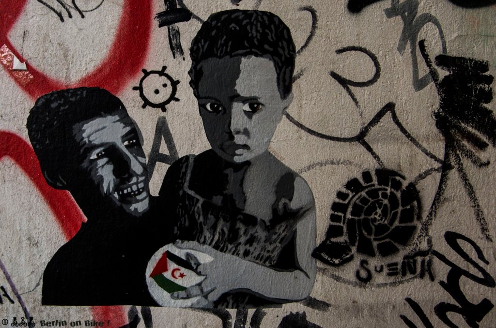 Pasteup in einem Friedrichshainer Hauseingang, offensichtlich ist das politisch gemeint, was zumindest die kleine Flagge in den Händen des Jungen nahelegt.