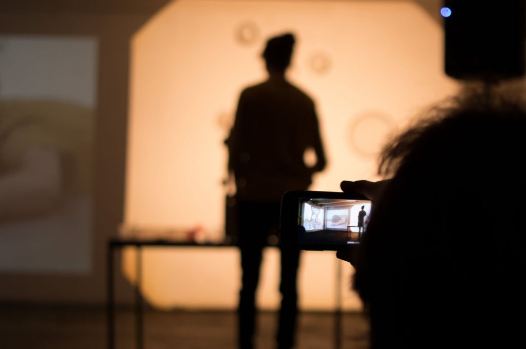 Eine Besucherin filmt eine Performance mit Ihrem Smartphone.