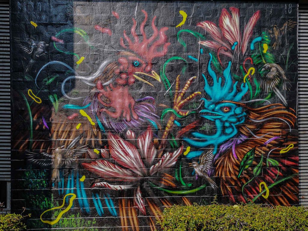 Sorry, but we missed the opportunity to find out the artists name, but its beautiful, so if you help us identifying the person behind this colourful cockfight, please do.