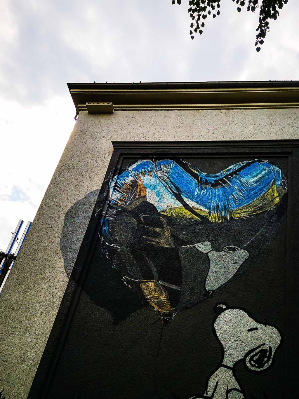 Mural of the cartoon character Snoopy looking at a giant reflecting balloon.