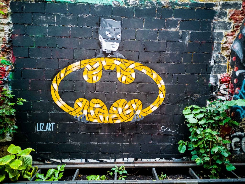Mural in Haus Schwarzenberg with a bat signal by Otto Schade and a cat woman paste-up by liz.art