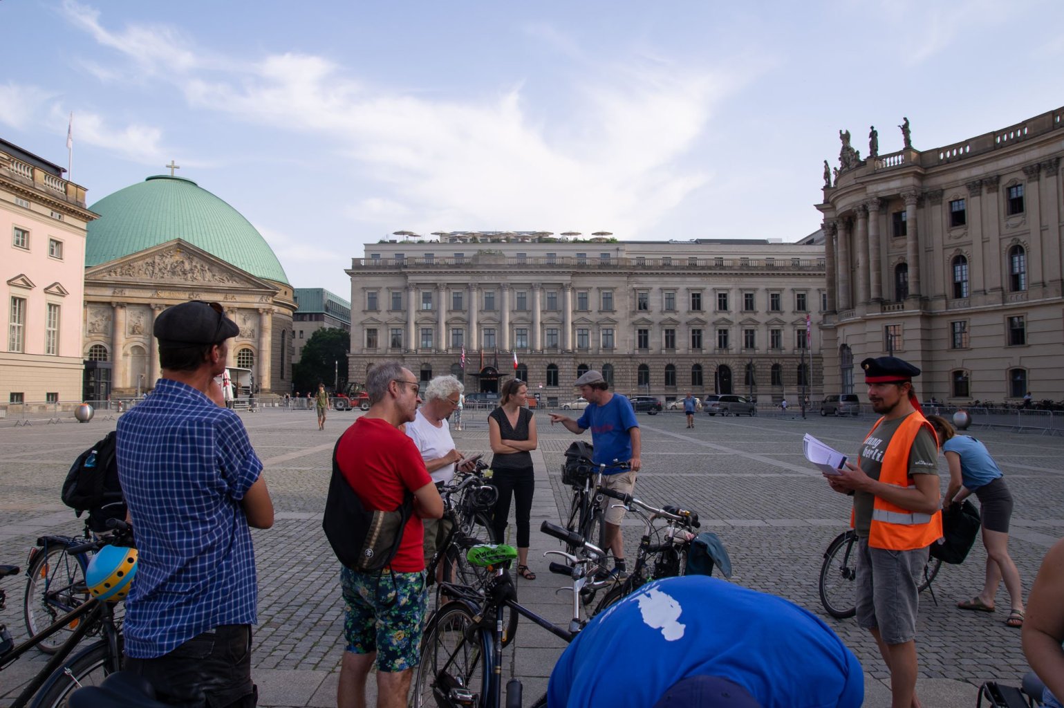 Eine Gruppe von Radfahrern stoppt auf dem Bebelplatz, ein Guide berichtet von sog Novemberrevolution.