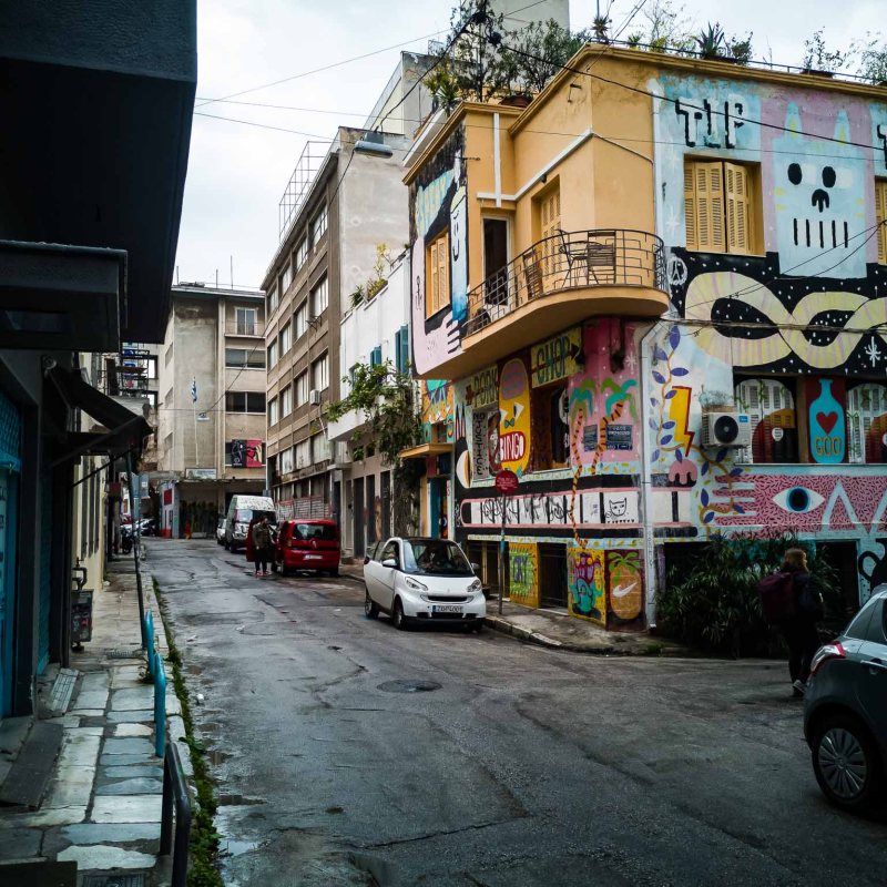 a narrow city street with cars parked on the side of a building