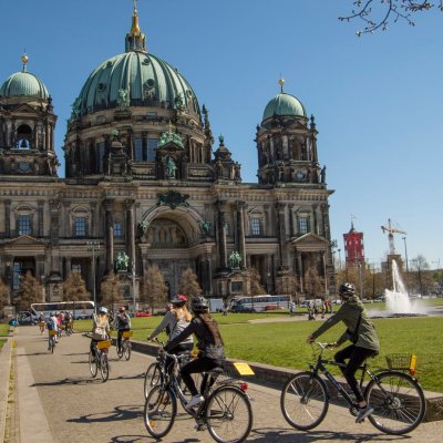 a person riding a bicycle in front of Berlin Cathedral