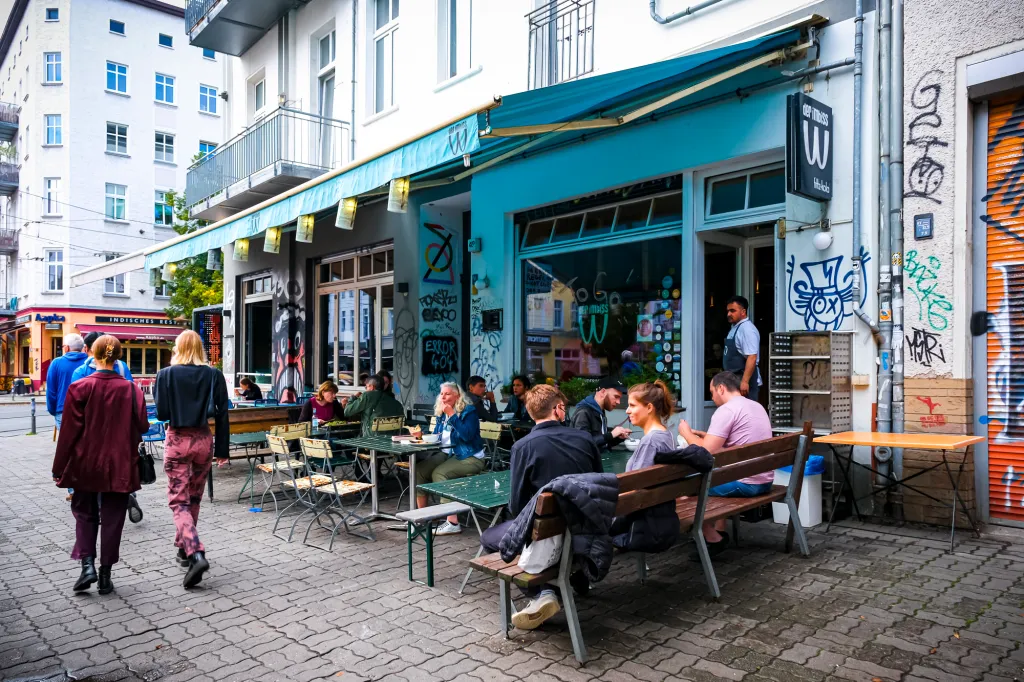 a group of people walking down a street in front of restaurant W der Imbiss