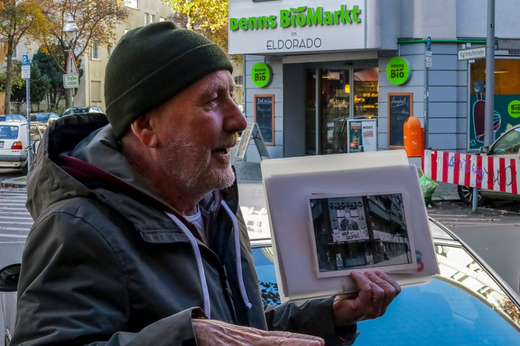tour guide Brendan in front of the site of the 1930s nightclub Eldorado in Schöneberg, showing a picture of the club's exterior