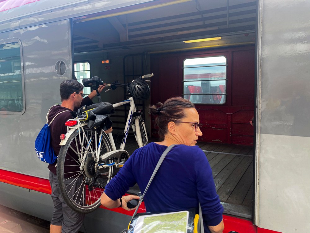 Menschen beim Rad einladen in einen Güterwaggon der österreichischen Bahn