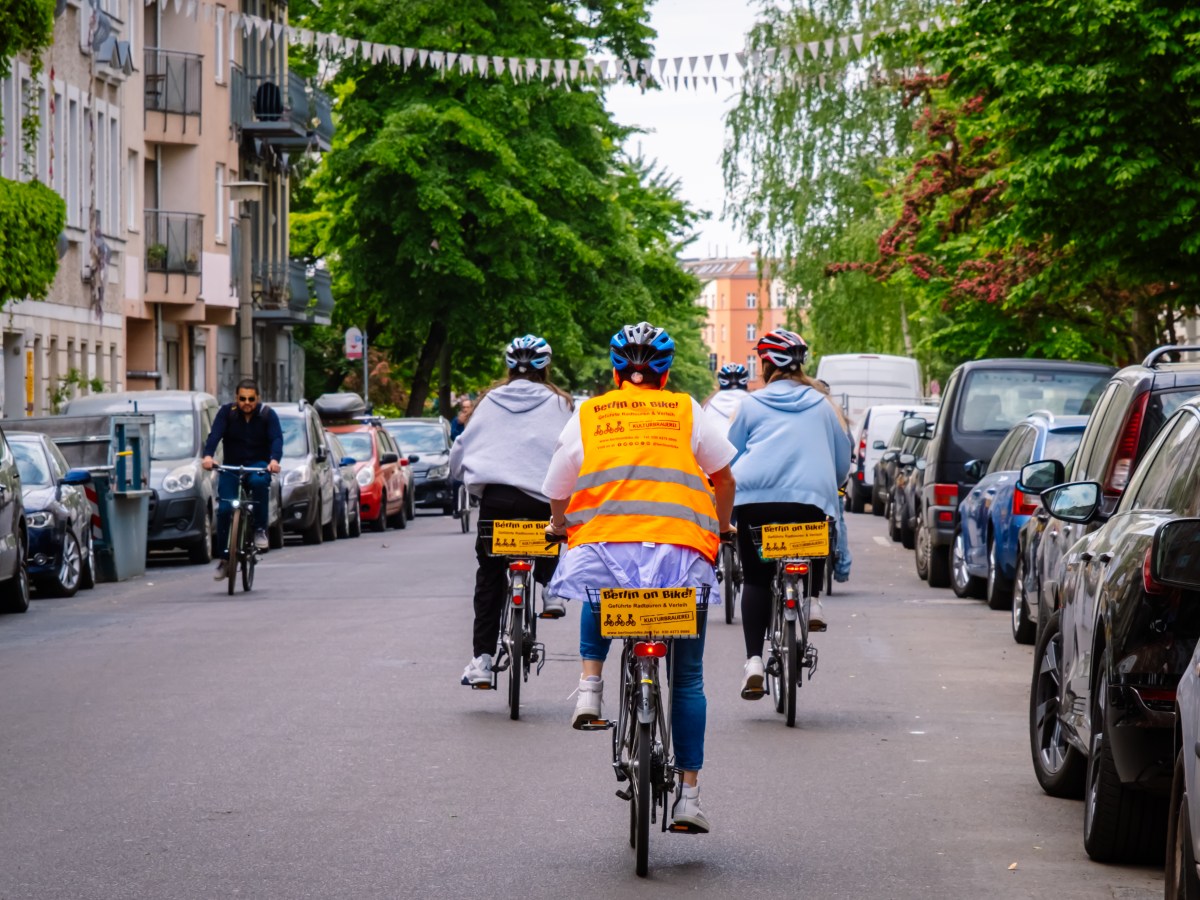 Cyclists wearing helmets and high-vis gear on a residential street.